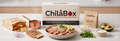 ChilaBox branded packaging box and paper bags displayed on a table alongside a prepared bowl of red chilaquiles, fresh avocados, cilantro, fresh cheese, and sliced grilled chicken breast.