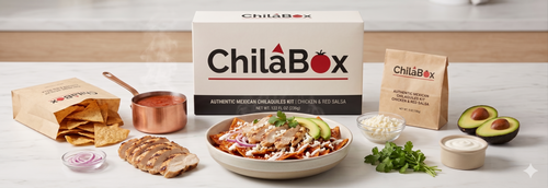 ChilaBox branded packaging box and paper bags displayed on a table alongside a prepared bowl of red chilaquiles, fresh avocados, cilantro, fresh cheese, and sliced grilled chicken breast.